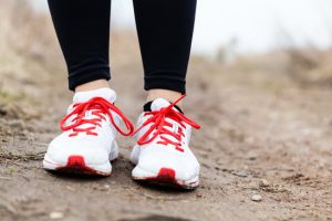 Walking or running woman legs and sport shoes on mountain dirt road, adventure fitness and exercising in autumn nature.